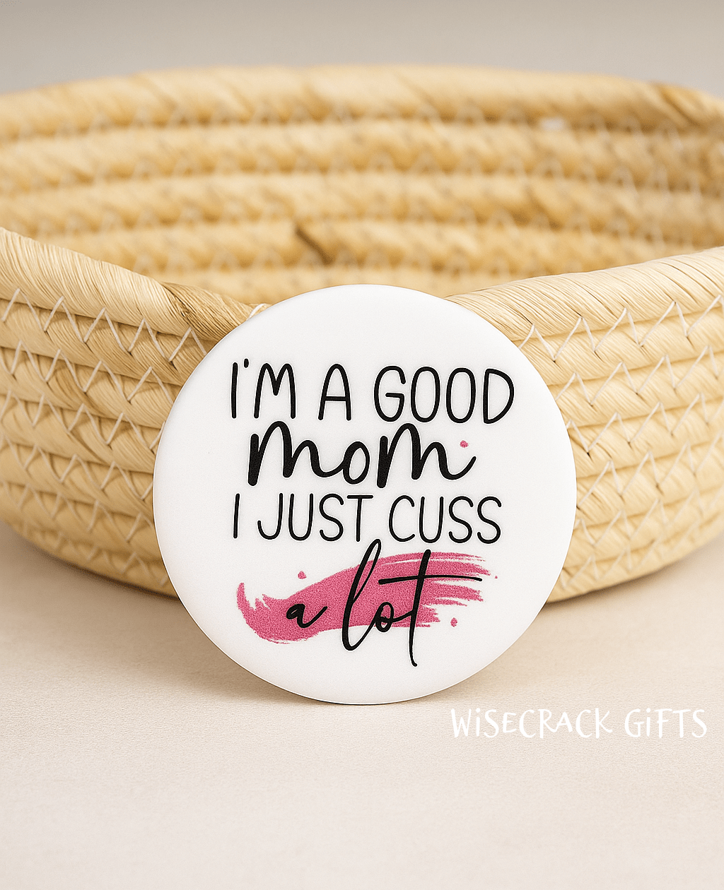 White button that reads I'm a good mom I just cuss a lot. Wisecrack Gifts is the creator with the name in the bottom corner.
